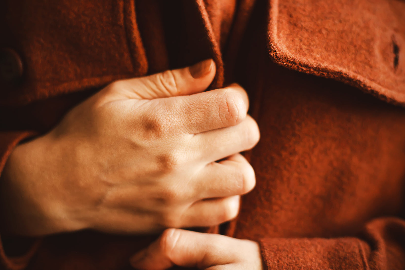 A woman wraps herself in a warm woolen ginger cozy shirt on a cold autumn day